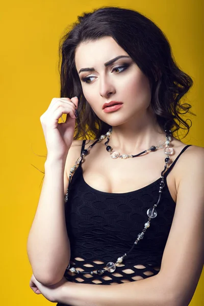 Portrait of a young beautiful dark haired concerned woman wearing black net top and glass beads looking worried and upset — Stock Photo, Image