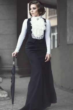 Siyah şemsiyesi eğilerek onu eski kale sütunlar arasında yürüyüş jabot ile eski moda elbise giyen zarif Victoria saç modeli ile muhteşem bir kadın portresi