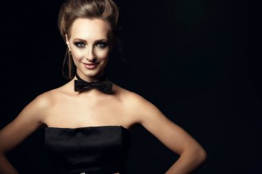 Portre portre kadar çok güzel kadınla glam gülümseyen ve kabarık saçlar boynunda siyah korse elbise ve papyon giyiyor. Siyah arka plan üzerine izole
