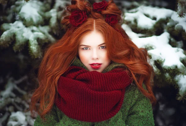Close up retrato de bela menina sorridente de cabelos vermelhos de olhos azuis com penteado criativo decorado com flores de malha posando na frente de árvores de fogo cobertas de neve — Fotografia de Stock