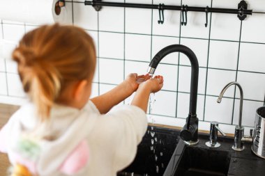 Sarışın bir kızın ellerini yıkaması, suyun altında sabun çalkalaması.