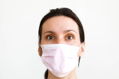 Tıbbi maske takan kadın kameraya bakıyor.