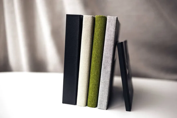 Four textile cover books standing on white table — Stock Photo, Image
