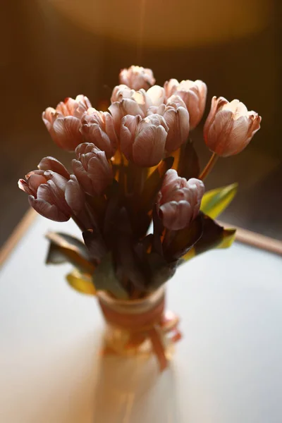 Ramo de tulipanes de pie sobre la mesa sobre fondo oscuro . — Foto de Stock