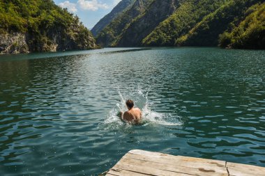 Adam suya su sıçratarak atlıyor.