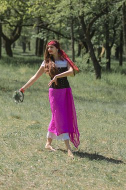 15. yüzyıl kostümlü, uzun saçlı güzel bir kız ormanda dans ediyor.