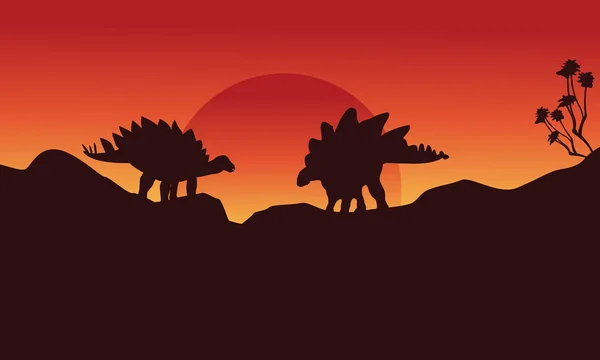 Silhouette de deux stegosaurus sur la falaise — Image vectorielle