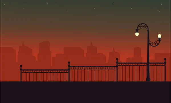 Farola con paisaje de valla en siluetas nocturnas — Vector de stock