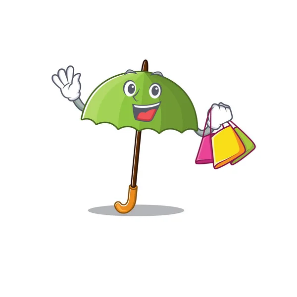 Happy rich green umbrella mascot design waving and holding Shopping bag — Stock Vector