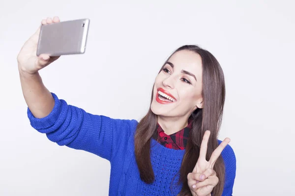 Beautiful young girl with a phone makes selfie. — Stock Photo, Image