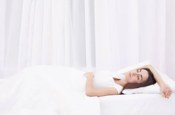 Красивая юная брюнетка спит в белой кровати. — стоковое фото