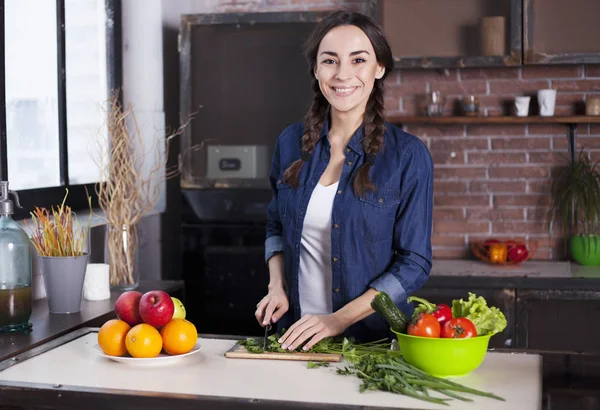 Jonge vrouw koken in de keuken thuis. Gezonde voeding. Dieet. Dieet Concept. Gezonde levensstijl. Thuis koken. Eten bereiden. Zeer mooie vrolijke jonge brunette vrouw die lacht. — Stockfoto