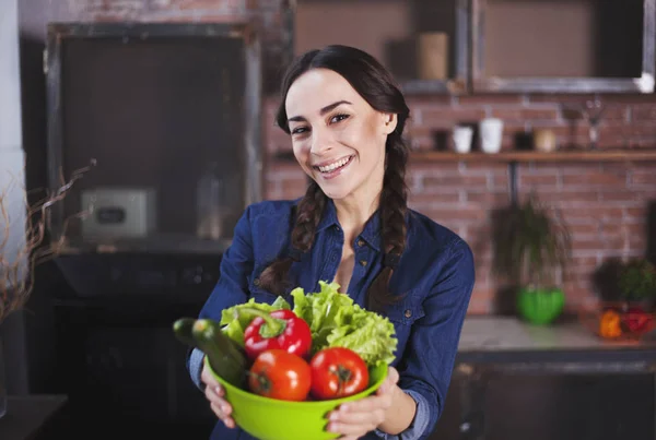 Jonge vrouw in de keuken. Gezonde voeding. Dieet. Dieet Concept. Gezonde levensstijl. Thuis koken. Eten bereiden. Zeer mooie vrolijke jonge brunette vrouw holding groenten en glimlachen. — Stockfoto