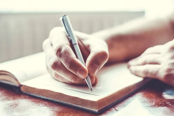 Mão masculina está escrevendo no bloco de notas — Fotografia de Stock