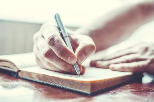 Mão masculina está escrevendo no bloco de notas — Fotografia de Stock