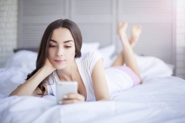 Yatak odasında telefon kullanan kadın