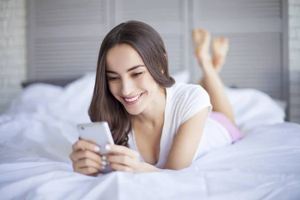 Mujer usando móvil en dormitorio — Foto de Stock