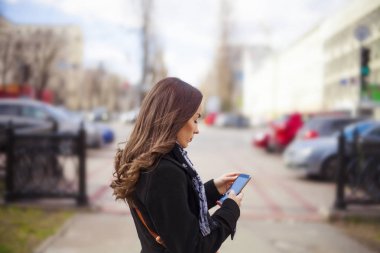 Akıllı telefon tutan genç bir kadın.
