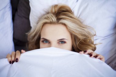 Genç kadın yatakta yatıyor. 