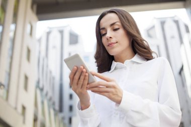 Akıllı telefon kullanan genç bir kadın.