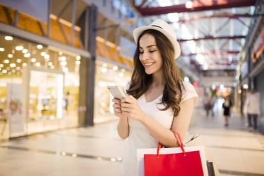 alışveriş merkezinde telefonu kullanan kadın