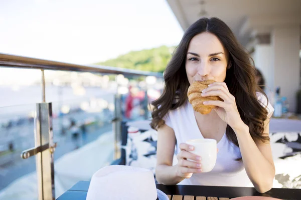 Donna mangiare croissant e bere caffè — Foto Stock