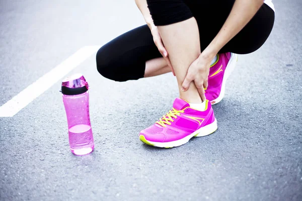 Female jogger holding aching ankle — Stock Photo, Image
