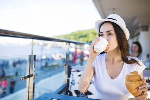 Жінка їсть круасан і п'є каву — стокове фото
