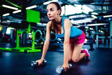 Dambıllarla egzersiz yapan kadın. 