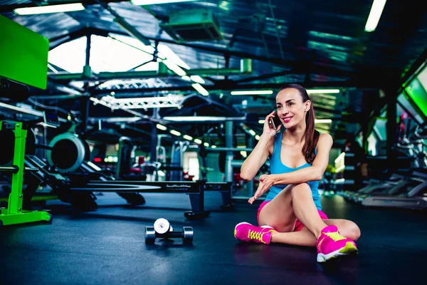 Woman using smartphone in fitness gym — Stock Photo, Image