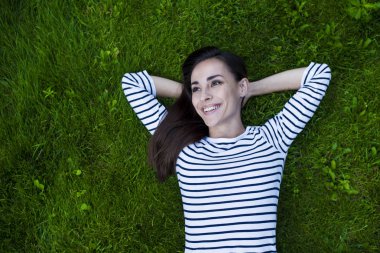 Genç kadın çimlerin üzerinde yatıyor.
