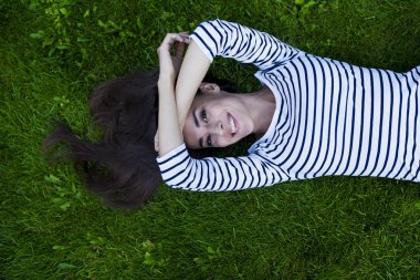 Genç kadın çimlerin üzerinde yatıyor.