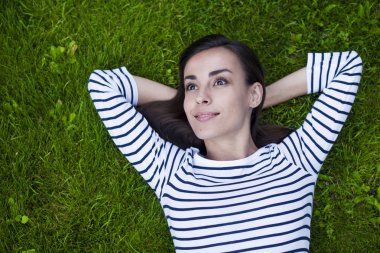 Genç kadın çimlerin üzerinde yatıyor.