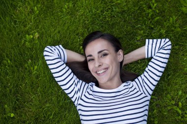 Genç kadın çimlerin üzerinde yatıyor.