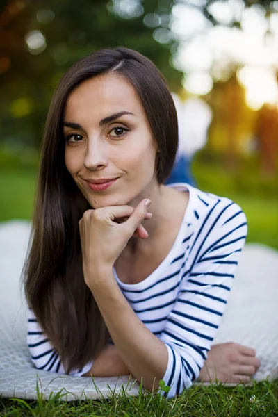 Genç kadın çimlerin üzerinde yatıyor.