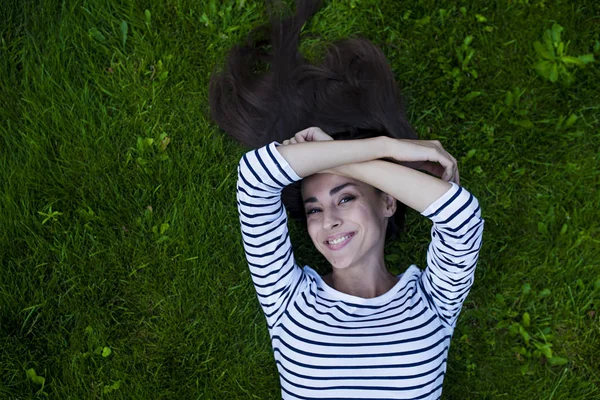 Genç kadın çimlerin üzerinde yatıyor.