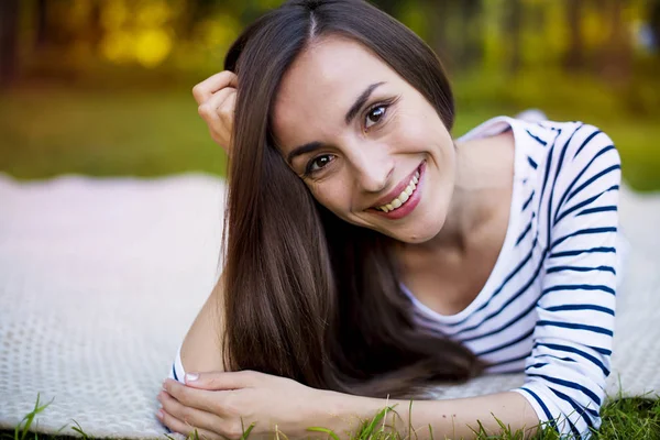 Genç kadın çimlerin üzerinde yatıyor.