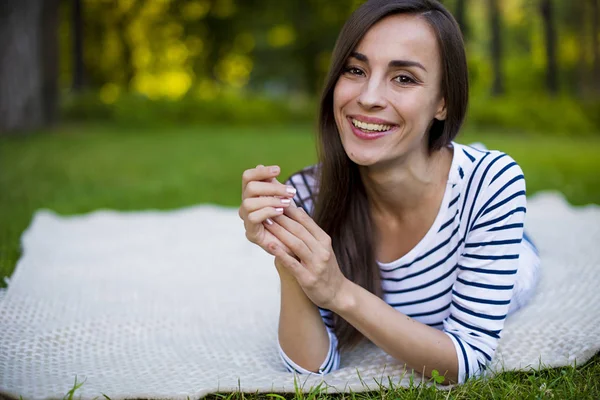 Genç kadın çimlerin üzerinde yatıyor.