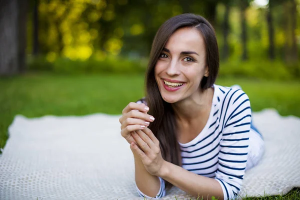 Genç kadın çimlerin üzerinde yatıyor.