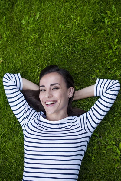 Genç kadın çimlerin üzerinde yatıyor.