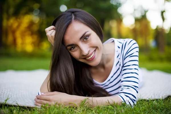 Genç kadın çimlerin üzerinde yatıyor.