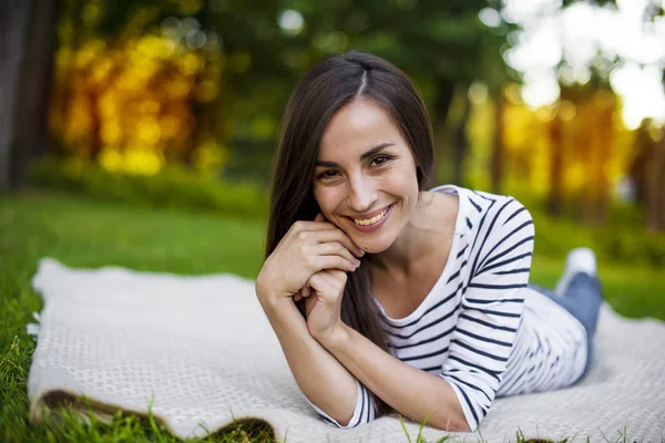 Genç kadın çimlerin üzerinde yatıyor.