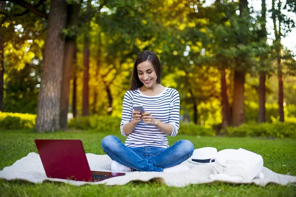 Donna che utilizza laptop e telefono cellulare all'aperto — Foto Stock