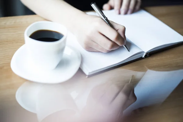 Weibchen schreiben mit Tasse Kaffee — Stockfoto
