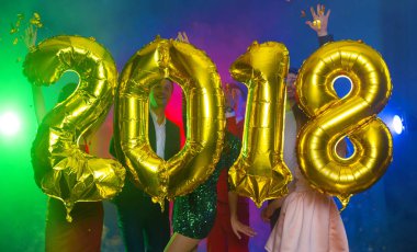 Arka plan dans eden bir grup genç insan üzerinde rakamlar şeklinde balonlar altın bileşimi. Yeni yıl 2018. Festival yeni yıl parti ya da disko.
