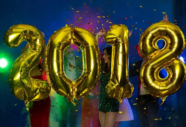 Arka plan dans eden bir grup genç insan üzerinde rakamlar şeklinde balonlar altın bileşimi. Yeni yıl 2018. Festival yeni yıl parti ya da disko.