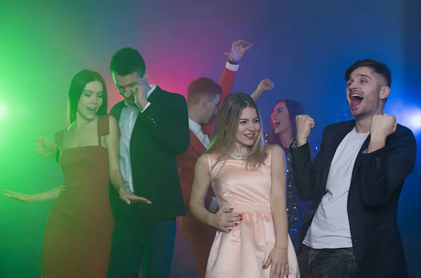 Group of young cheerful and happy friends are dancing at a party. Man and woman dancing in the foreground in front of the camera