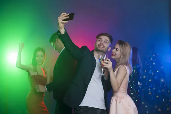 Friends rest and dance in the club on holiday. The guy with the girl do selfie on the phone