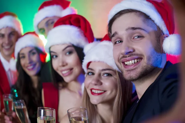 一组在圣诞老人的微笑的朋友在新年晚会上拍照或做自拍 — 图库照片