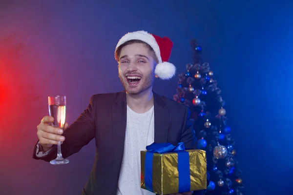 良い新年 そしてメリー クリスマスシャンパン グラスでサンタ クロースの帽子の若いビジネスマン達とクリスマス ツリーの背景手にギフトを笑顔が美しい — ストック写真